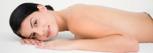 Brünette lächelnd auf Massagetisch liegend — Stockfoto