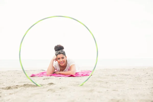Femme souriante regardant la caméra à travers hula hoop — Photo