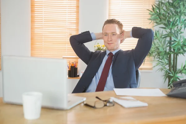 Relaxed businessman sitting back at desk — Stock Photo, Image