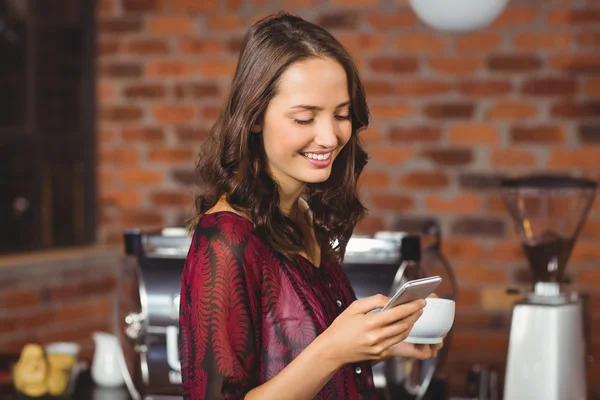 Mujer bonita sosteniendo una taza de café y mensajes de texto —  Fotos de Stock