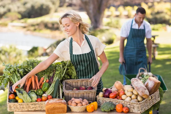 Une agricultrice rangeant une table de nourriture locale — Photo