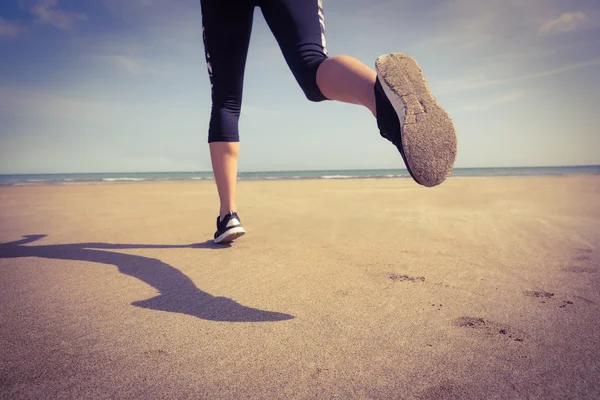 Подходящая женщина, бегущая по песку — стоковое фото