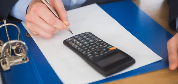 Empresário usando uma calculadora e escrita — Fotografia de Stock