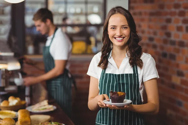 Όμορφη σερβιτόρα κρατώντας ένα πιάτο με muffin — Φωτογραφία Αρχείου