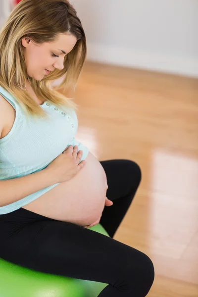 Беременная женщина сидит на мяче для упражнений — стоковое фото