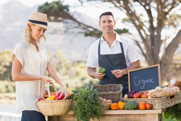 Smiling farmer selling red and green peppers — Stock Photo, Image