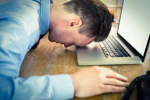 Стрессовый бизнесмен с головой на ноутбуке — стоковое фото
