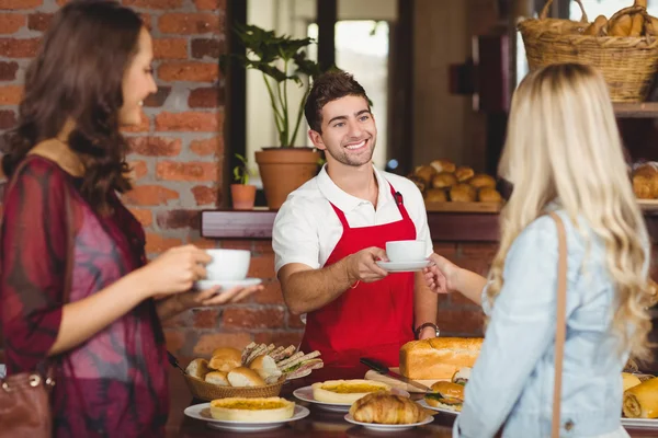 Lachende ober serveren een koffie aan een klant — Stockfoto