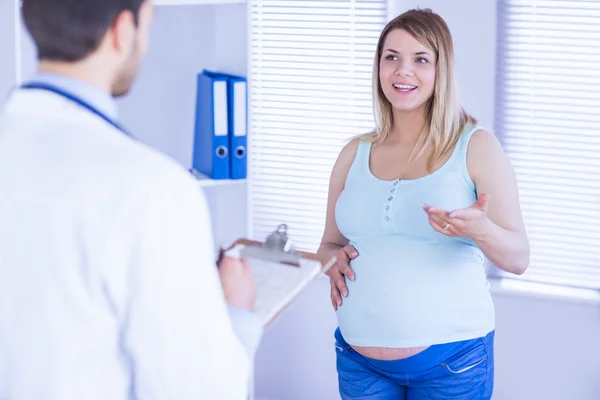 Sorridente paziente incinta che parla con il medico — Foto Stock