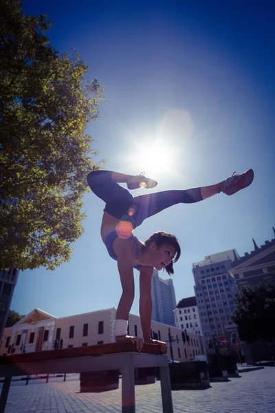 Femme athlétique exécutant handstand sur banc — Photo