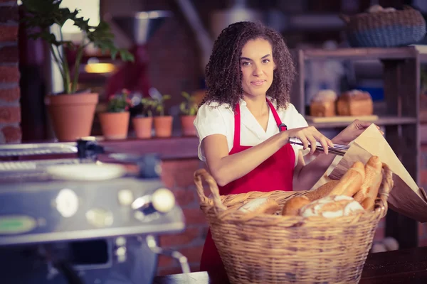 Cameriera sorridente mettere il pane in un sacchetto di carta — Foto Stock