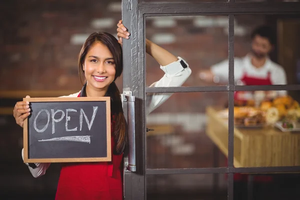 Улыбающаяся официантка показывает доску с открытым знаком Стоковое Фото