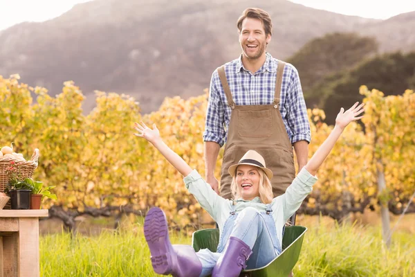 Feliz pareja en dungarees empujando una carretilla Imágenes De Stock Sin Royalties Gratis