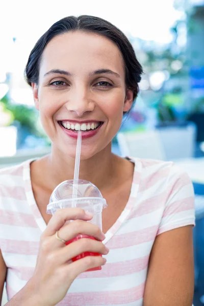 Smiling brunette woman enjoying her milkshake Royalty Free Stock Images