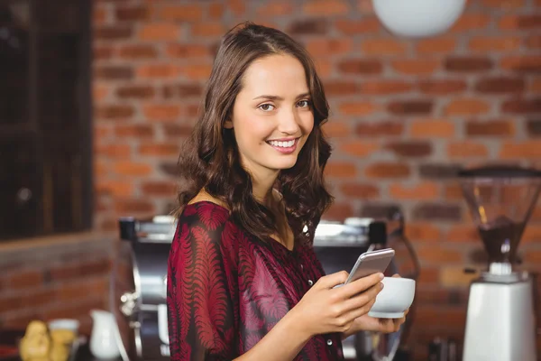 Mujer bonita sosteniendo una taza de café y mensajes de texto —  Fotos de Stock