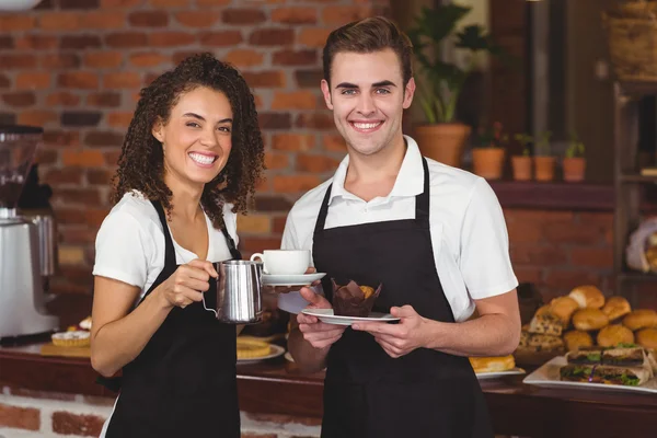 Официант и официантка улыбаются в камеру — стоковое фото