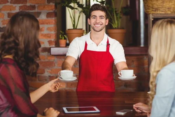 Улыбающийся официант, подающий кофе клиентам — стоковое фото