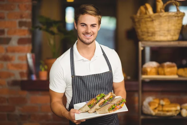 Camarero guapo sosteniendo un plato de sándwiches — Foto de Stock