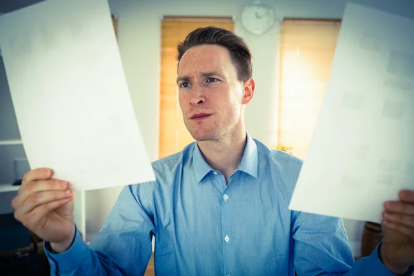 Hombre de negocios serio sosteniendo dos hojas de papel — Foto de Stock