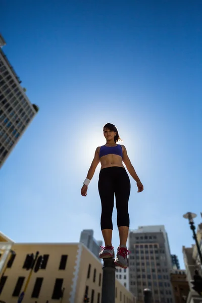 Athletic woman balancing on bollard — Stock Photo, Image