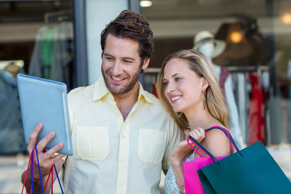 Pareja con bolsas de compras mirando a la tableta —  Fotos de Stock