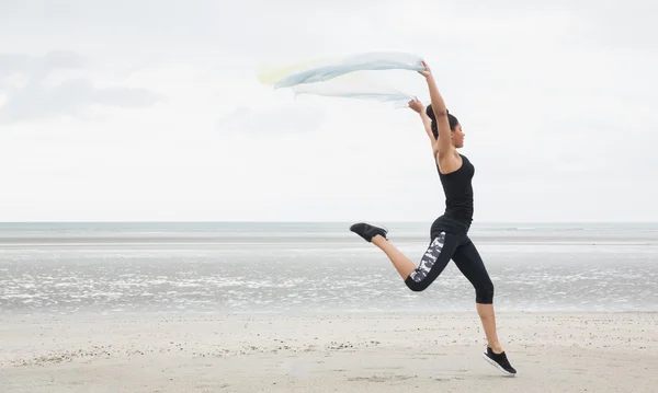 Fit girl leaping with scarf — Stock Photo, Image