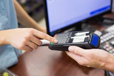 Woman at cash register paying with credit card clipart