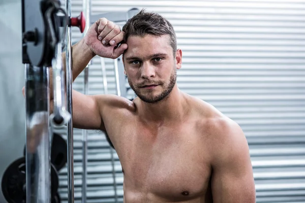 Portret van gespierde man leunend tegen gym apparatuur — Stockfoto