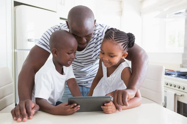 Lycklig familj på bord med digitala tablett — Stockfoto