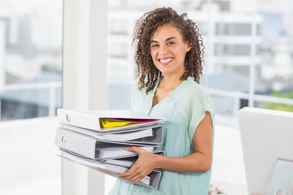 Smiling businesswoman carrying a stack of folders — Stock Photo, Image