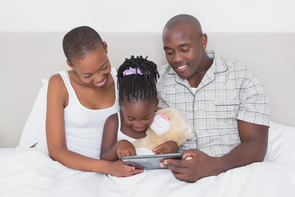 Casal bonito usando tablet com sua filha na cama — Fotografia de Stock