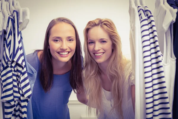 Amigos felizes olhando através do rack de roupas — Fotografia de Stock