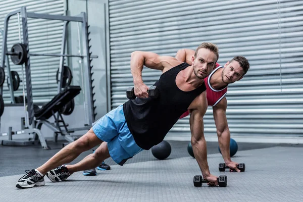 Homens musculosos fazendo uma prancha lateral — Fotografia de Stock