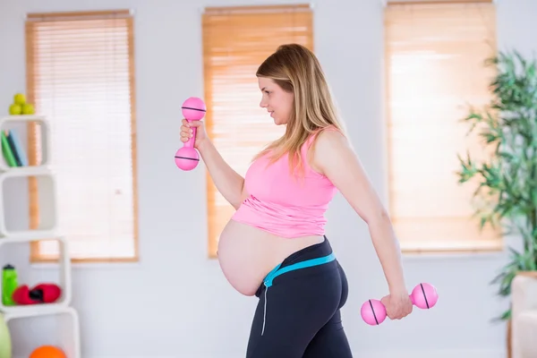Беременная женщина держит гантели — стоковое фото