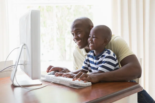 Счастливый улыбающийся отец с сыном за компьютером — стоковое фото