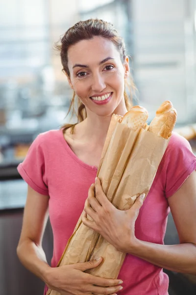 Smiling young brunette with baguettes — Stock Photo, Image