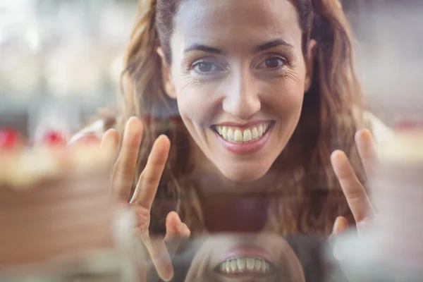 Pretty brunette looking at camera through the glass — Stock Photo, Image