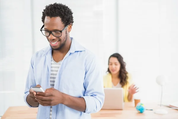 Sorrindo homem posando na frente de seu colega usando smartphone — Fotografia de Stock