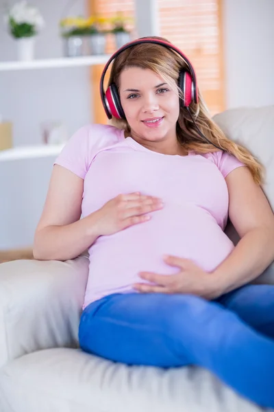 Lächelnde Schwangere beim Musikhören — Stockfoto