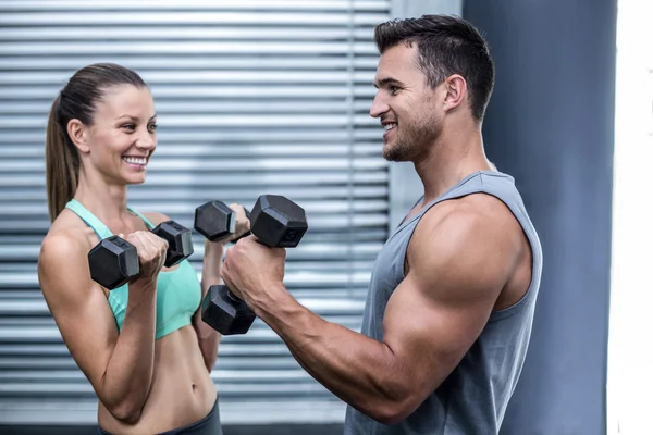 Un couple musclé soulevant haltères — Photo