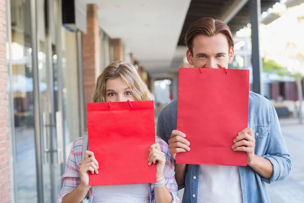 Ein glückliches Paar versteckt sich hinter roten Säcken — Stockfoto