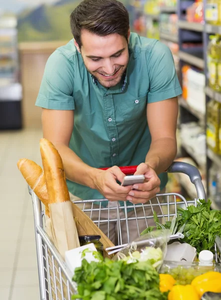 Lächelnder Mann kauft Produkte und benutzt sein Smaprtphone — Stockfoto