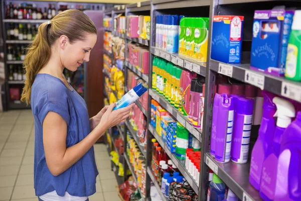 Jolie brune réfléchie regardant le produit dans l'étagère — Photo