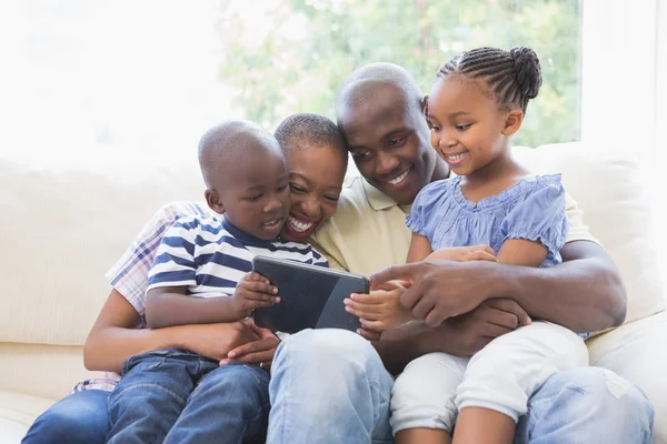 Família feliz no sofá usando tablet digital — Fotografia de Stock