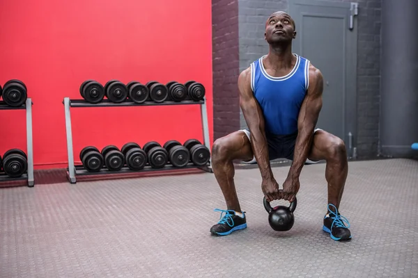 Kaslı adam bir kettlebell kaldırma — Stok fotoğraf