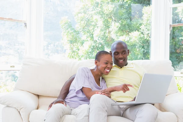 Feliz casal sorrindo usando laptop no sofá — Fotografia de Stock