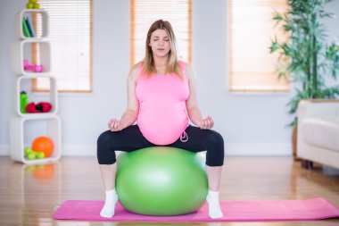 Pregnant woman doing yoga clipart