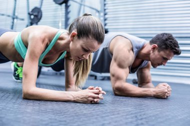 Muscular couple doing planking exercises clipart