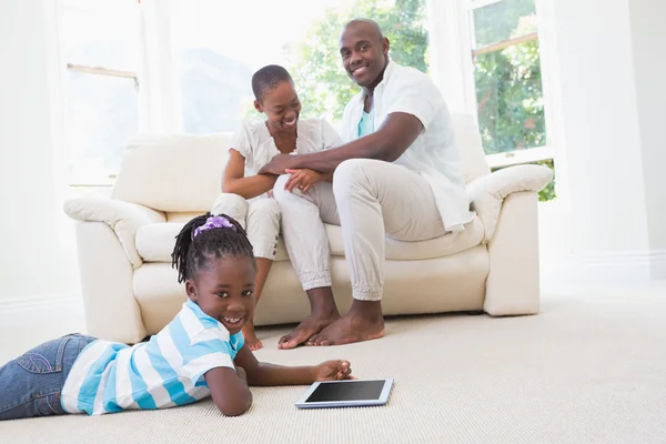 Ganska par sitter på soffan och deras dotter med digital — Stockfoto