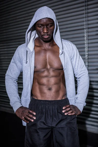 Jeune bodybuilder dans un sweat à capuche regardant avec inquiétude au sol — Photo